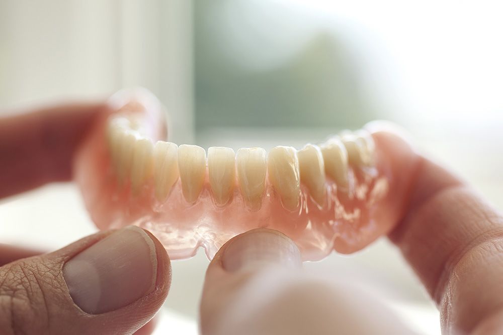 Hands holding lower denture